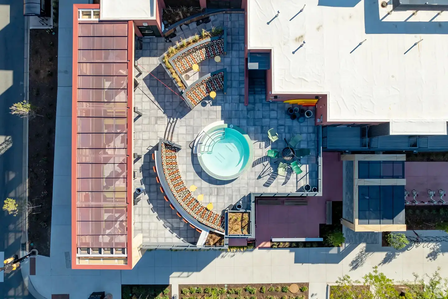 Rooftop pool with modern style and a fire pit with chairs nearby.